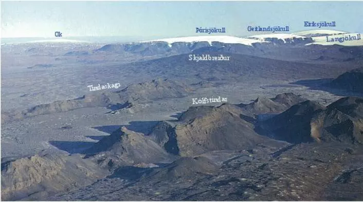 Figur 3: Utsikt mot nordvest, på skrå over den vestlige riftsonen. De bratte ryggformete fjellene i forgrunnen er dannet ved subglasiale utbrudd i den siste delen av siste istid. Riftsonebunnen mellom ryggene er dekket av lavastrømmer som jevner ut landskapet. Skjoldvulkanen Skjaldbreiður bak ryggene er dannet i ett sammenhengende, og voluminøst utbrudd av lava like etter isavsmeltingen. I bakgrunnen sees flere isdekte bordfjell i utkanten av den store isbreen Langjökull. Skjoldvulkanen Ok efra siste mellomistid er også synlig. Klikk her for større versjon. (Foto: Kristján Sæmundsson)