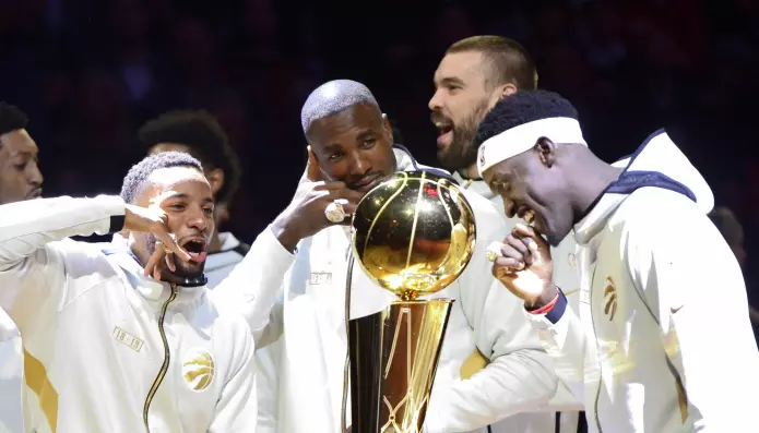Basketspillere fra laget Toronto Raptors ser blide ut når de står rundt NBA-pokalen før den avgjørende kampen mot the Golden State Warriors.