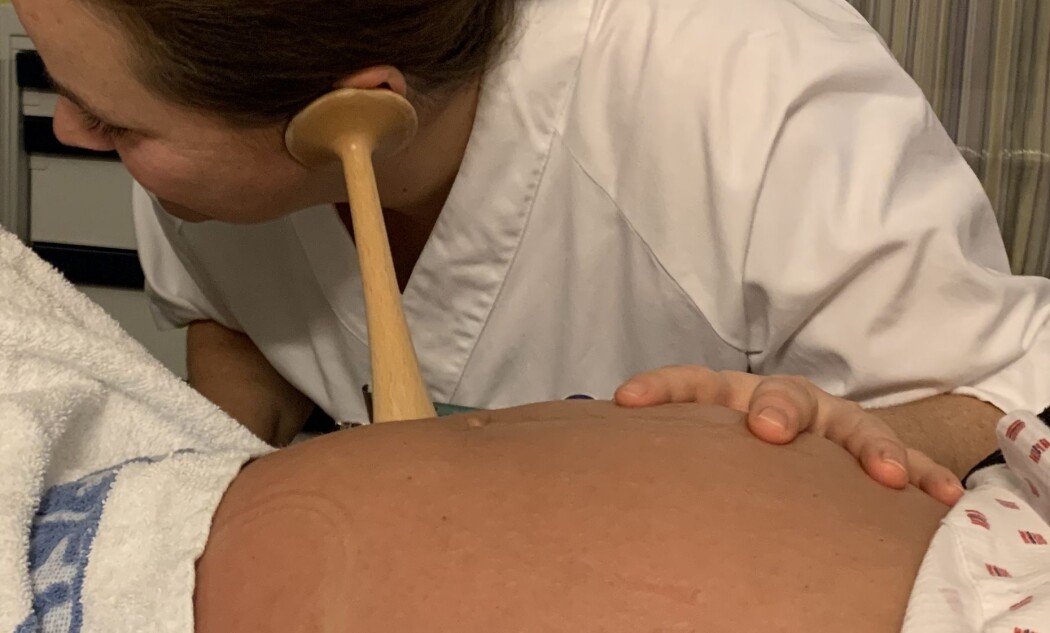 Jordmor og forsker Christina Hernandez Engelhart lytter til barnets hjerte med et jordmordstetoskop av tre. Jordmor og forsker Christina Hernandez Engelhart lytter til barnets hjerte med et jordmordstetoskop av tre.