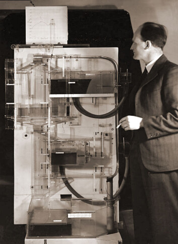 Bill Phillips med den analoge vanndatamaskinen Moniac. (Foto: London School of Economics/Wikimedia Commons) Bill Phillips med den analoge vanndatamaskinen Moniac. (Foto: London School of Economics/Wikimedia Commons)