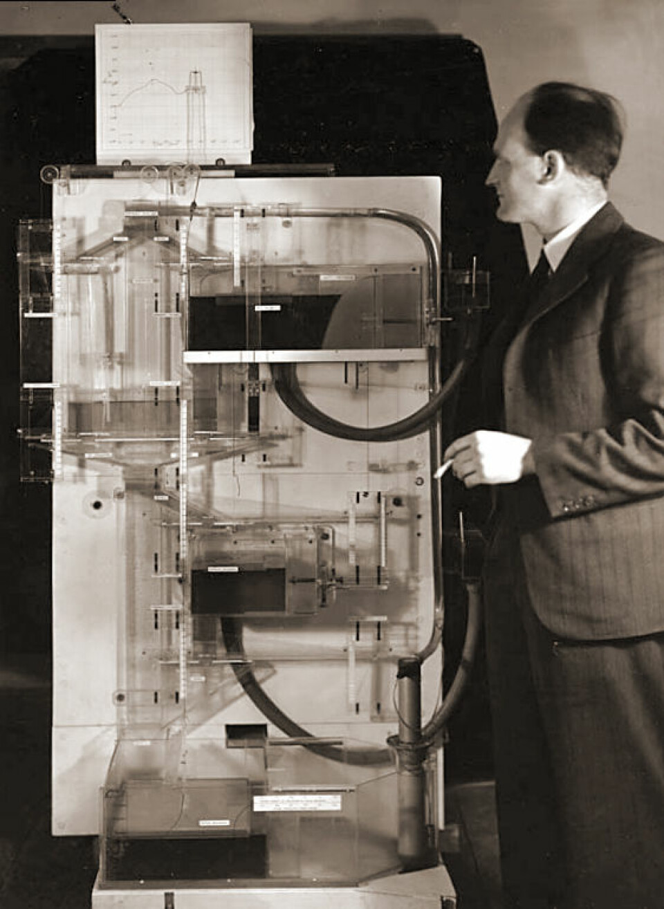 Bill Phillips med den analoge vanndatamaskinen Moniac. (Foto: London School of Economics/Wikimedia Commons)