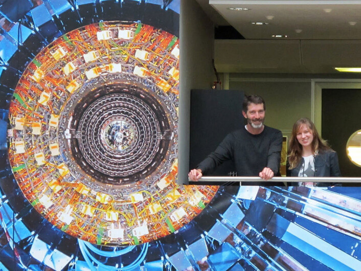 Higgs-jegerne Alex Read og Lillian Smestad ved en dekorert vegg i CERN-laboratoriet. (Foto: UiO) Higgs-jegerne Alex Read og Lillian Smestad ved en dekorert vegg i CERN-laboratoriet. (Foto: UiO)