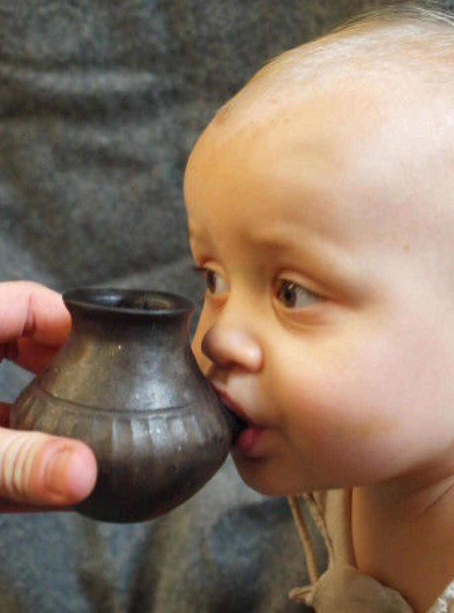 Her får en moderne baby drikke fra en kopi av en tutekopp.