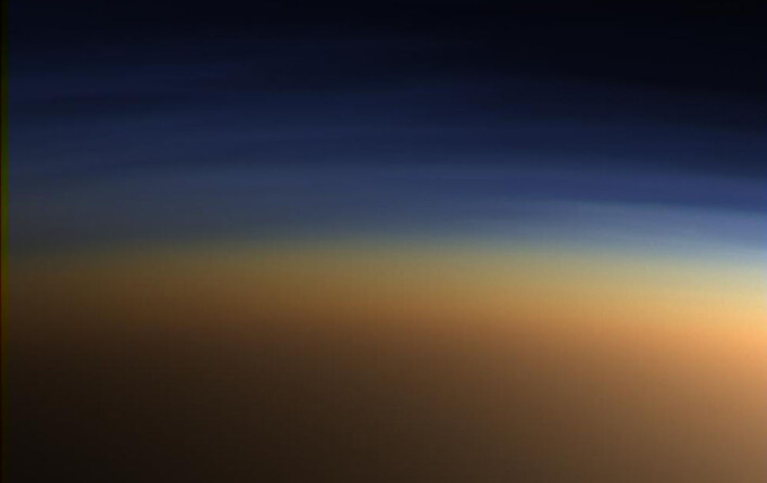 Dette bildet er tatt av Cassini da den passerte Titan i 2005. De øvre lagene av den tykke atmosfæren sprer blått og ultrafiolett lys, slik at tåken ser orange ut. (Foto: NASA) Dette bildet er tatt av Cassini da den passerte Titan i 2005. De øvre lagene av den tykke atmosfæren sprer blått og ultrafiolett lys, slik at tåken ser orange ut. (Foto: NASA)