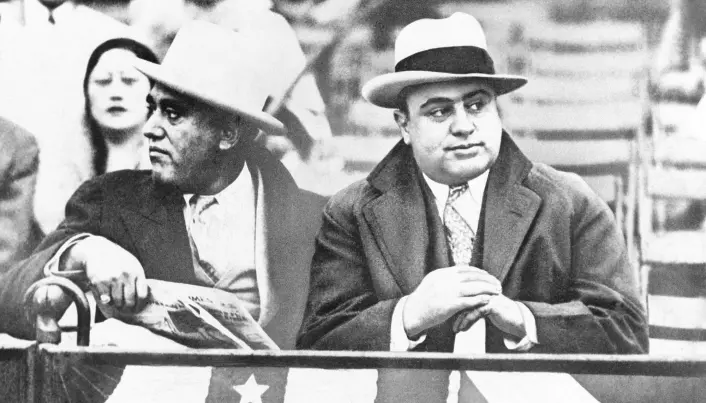 Gangsteren Al Capone (t.h.) på en amerikansk fotballkamp i Chicago. Al Capone tjente millioner av dollar på ulovlig spritsalg.