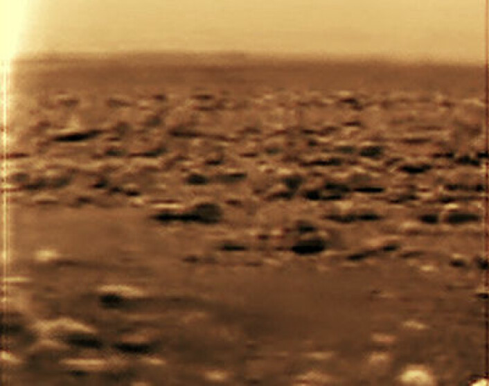 Romsonden Huygens tok dette bildet fra overflaten av Titan. Fotografiet er digitalt renset og bearbeidet for å få fram detaljer. Dette er et utsnitt i breddeformat. (Foto: NASA)