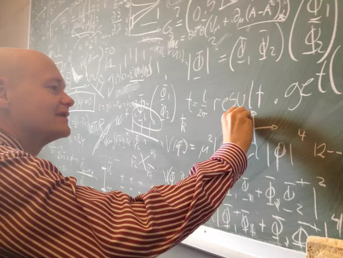 Professor Are Raklev ved Fysisk institutt, Universitetet i Oslo tegner på tavla på kontoret sitt. (Foto: Ingrid Spilde)