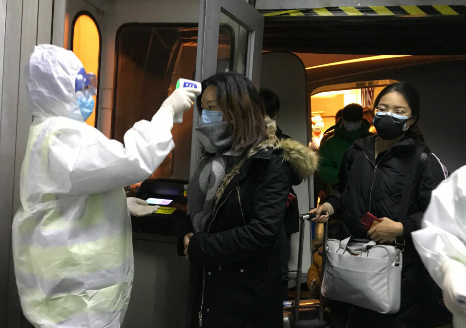 Helsearbeidere ved flyplassen i Beijing sjekker kroppstemperaturen til passasjerer fra Wuhan. 571 mennesker skal ha blitt smittet av det nye coronaviruset.