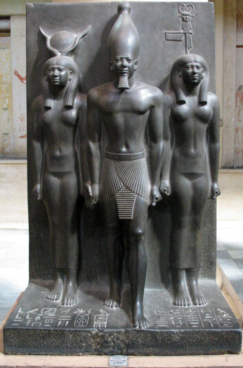 Menkaure, avbildet med gudinnen Hathor (t.h.) og en kvinnelig fremstilling av byen Diospolis Parva til venstre. (Foto: Wikimedia Creative Commons) Menkaure, avbildet med gudinnen Hathor (t.h.) og en kvinnelig fremstilling av byen Diospolis Parva til venstre. (Foto: Wikimedia Creative Commons)