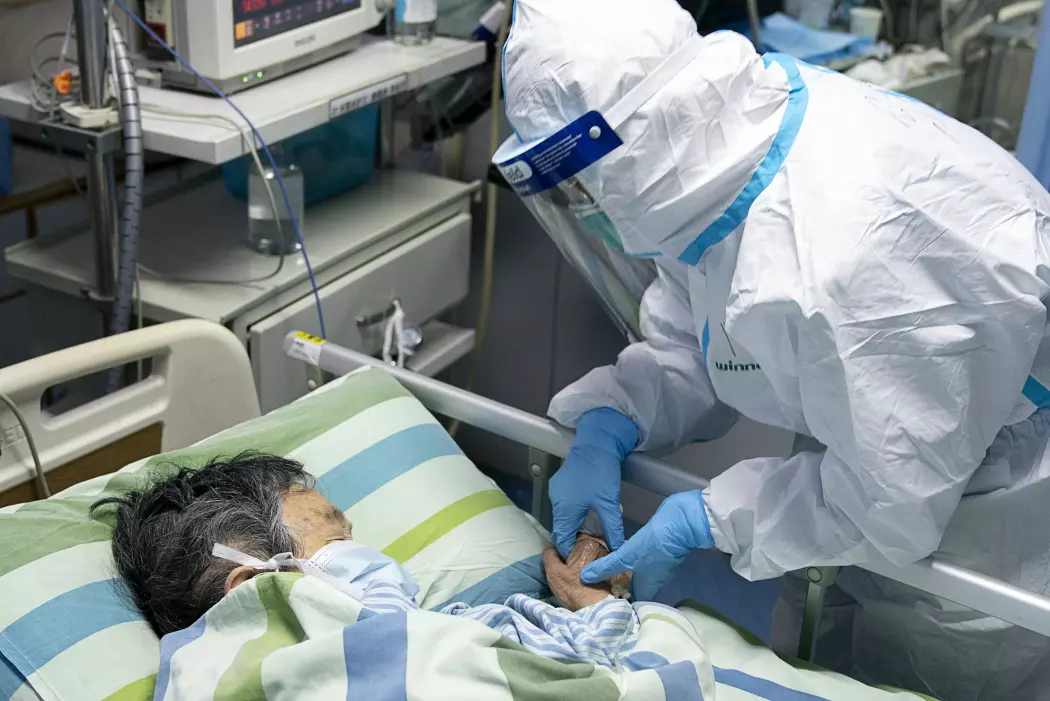 En helsearbeider ser til en innlagt på et sykehus i Wuhan, byen hvor virusutbruddet har rammet hardest.