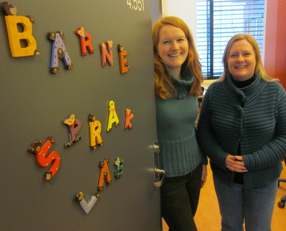 Kristine Bentzen (til venstre) og Merete Anderssen ivrer for tospråkllighet hos barn. Her foran døra til Barnespråklaboratoriet på Universitetet i Tromsø. (Foto: UiT)