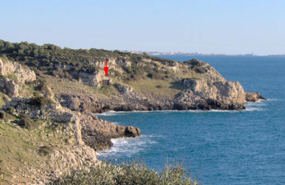 Grotta del Cavallo ligger ved en bukt på kysten av Puglia i Sør-Italia. Åpningen er merket med en rød pil. Hulen ligger i naturreservatet Regional National Park of Portoselvaggio. Bukta heter Uluzzo, samme navn har arkeologene brukt på funn av denne typen fra det sentral og sørlige Italia. (Foto: Annamaria Ronchitelli)