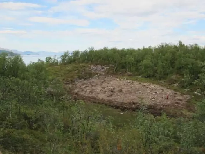 Litt av utgravingsområdet bak Larshaugen i Melsvik. I bakgrunnen sees Altafjorden og Isnestoften i det fjerne. Den avdekkede delen av steinbruddet i berget sees til venstre for utgravingsområdet. (Foto: Tromsø Museum - Universitetsmuseet)