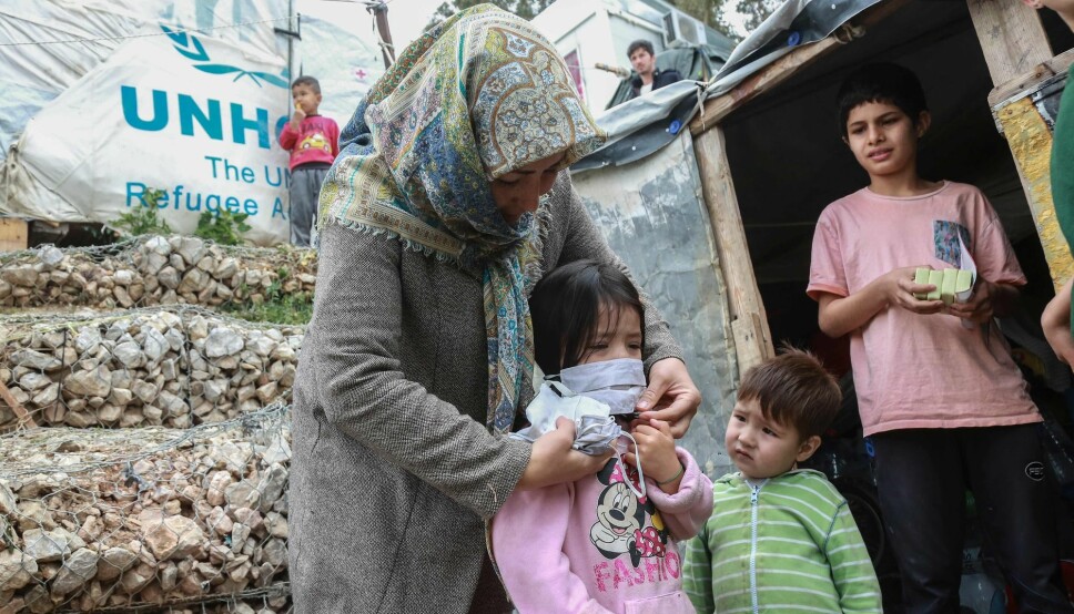 A woman helps a child with a mask after members of NGO 'Team Humanity' gave out handmade protective face masks to migrants and refugees in the camp of Moria in the island of Lesbos on March 28, 2020 as as the country is under lockdown to stop the spread of Covid-19 disease caused by the novel coronavirus.