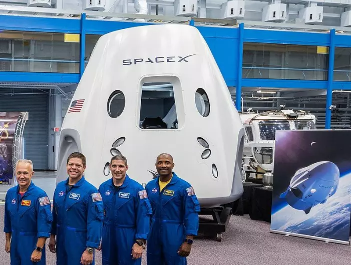 De fire første astronautene som skal fly med Crew Dragon, foran en modell av romskipet.