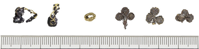 De seks edelmetallgjenstandene funnet i grava. Helt til venstre er de to gullringene med hver sin perle, så den lille gullperla og de tre sølvplatene med forgylte tråder til høyre. De seks edelmetallgjenstandene funnet i grava. Helt til venstre er de to gullringene med hver sin perle, så den lille gullperla og de tre sølvplatene med forgylte tråder til høyre.