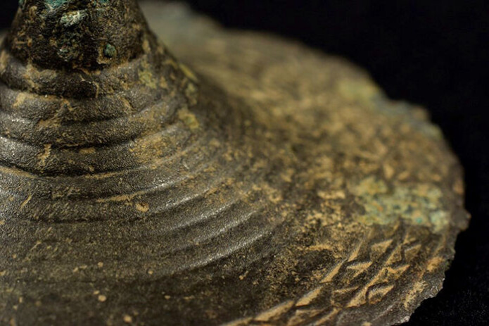 Figur 5: Detalj av tutulus fra Killi Megård, Dovre. Datert til 1500–1300 f. Kr. og funnet av Roy Fjerdingby i 2015. Dekorert med konsentriske sirkler og ytterst to rader med sikksakkdekor. På baksiden er det en liten hempe. Figur 5: Detalj av tutulus fra Killi Megård, Dovre. Datert til 1500–1300 f. Kr. og funnet av Roy Fjerdingby i 2015. Dekorert med konsentriske sirkler og ytterst to rader med sikksakkdekor. På baksiden er det en liten hempe.