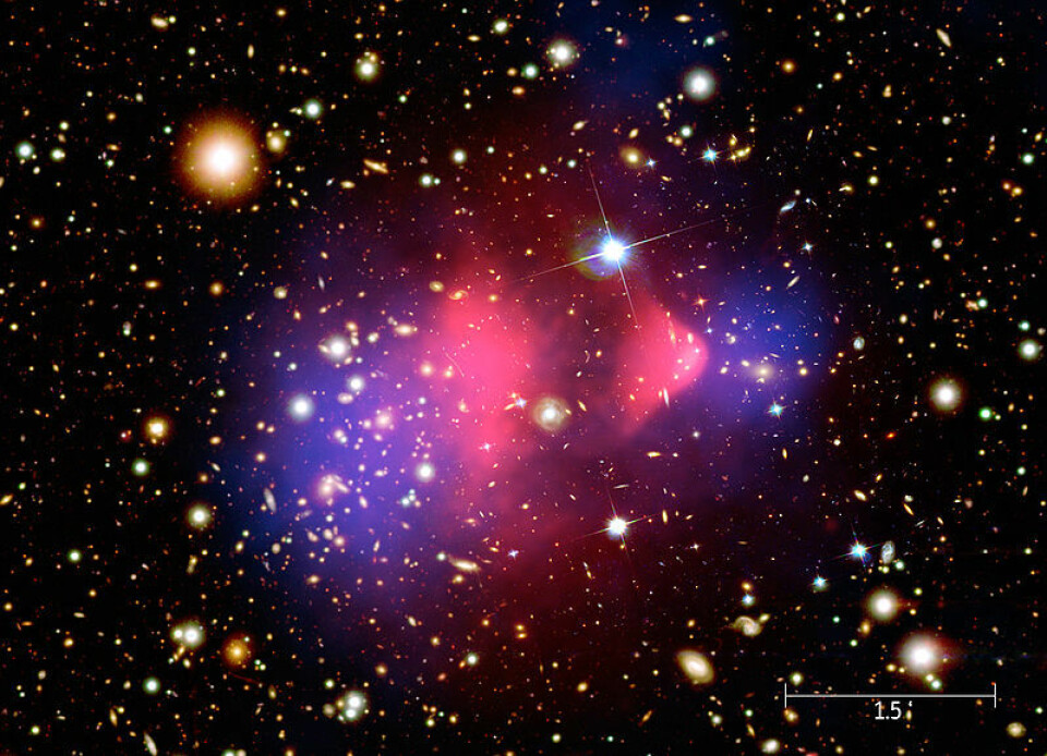 Det røde området i midten viser røntgenstråling fra to kolliderende galaksehoper, fotografert med romteleskopet Chandra. Vanlig materie ble bremset opp i kollisjonen (rødt), mens den mørke materien fortsatte tvers gjennom, upåvirket (blått). Den mørke materien er tegnet inn i fotografiet, da den ikke kunne påvises direkte, bare måles ut fra hvordan tyngdekreftene deres avbøyde lysstråler fra galaksene. (Foto: NASA/CXC/M. Weiss)