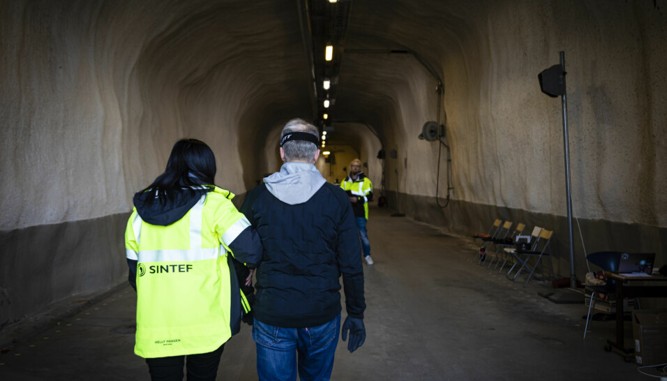 Here we see one of the research subjects being led through the tunnel, wearing glasses that make it impossible for him to see where he is going. The sound system developed by the researchers simulates the noises made by the tunnel fans during a fire, while at the same time testing the new auditory guidance system.