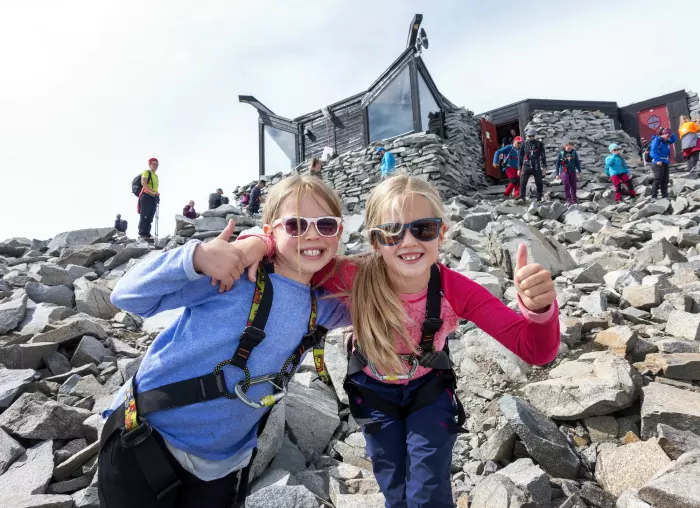 Å bestige Galdhøpiggen er noe flere nordmenn kanskje gjør i sommer. Her to jenter som var på toppen av Norges høyeste fjell sommeren for to år siden.