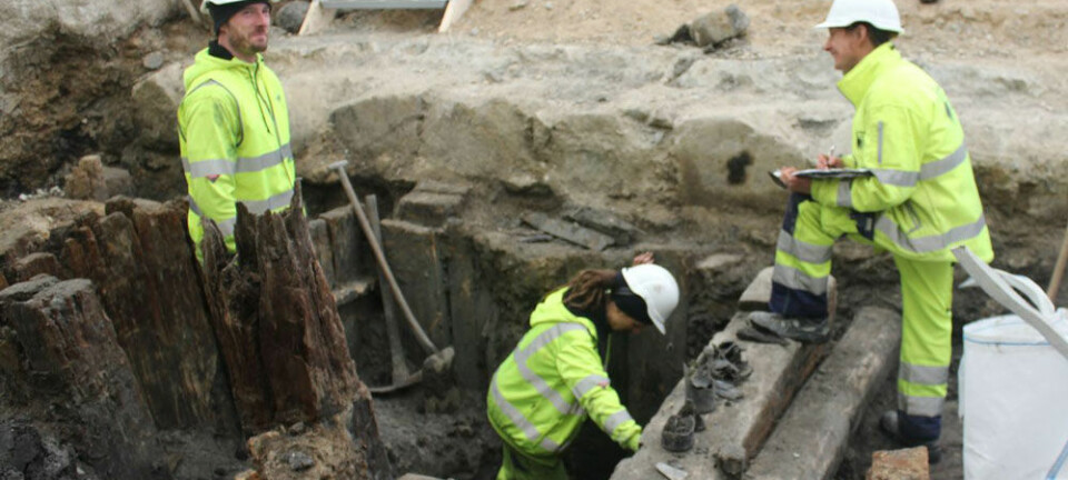 Her holder tre arkeologer på å grave ut en de mange kassene hvor de blant annet har funnet rester fra flere glassflasker. Anne Marie Lykkegaard