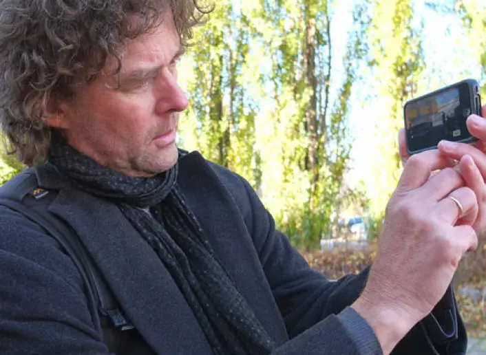 Professor Gunnar Liestøl demonstrerer hvordan du kan ta bilder av den virtuelle og den virkelige verden samtidig. (Foto: Norunn K. Torheim)
