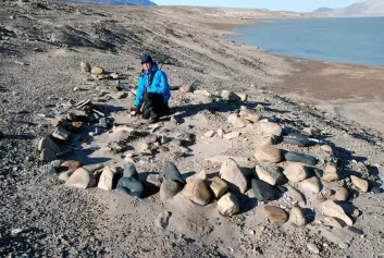 I det ørkenaktige landskapet ved Independence-fjorden lagde de første paleo-eskimoene sine hjem. Her sitter Astrid Lyså, forsker fra Norges Geologiske Undersøkelse, i restene etter ett av dem. (Foto: Eiliv Larsen)