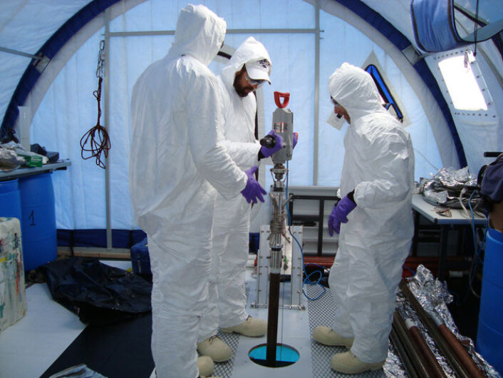Biletet viser forskarteamet i ferd med å bore gjennom isen i Lake Vida. For å unngå å forureine vassprøvane er forskarane kledd i sterile drakter. (Foto: Desert Research Institute, Emanuele Kuhn) Biletet viser forskarteamet i ferd med å bore gjennom isen i Lake Vida. For å unngå å forureine vassprøvane er forskarane kledd i sterile drakter. (Foto: Desert Research Institute, Emanuele Kuhn)