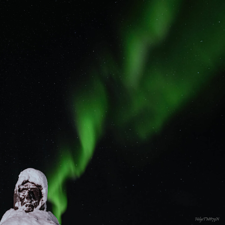 Statuen av Roald Amundsen i Ny-Ålesund lyser opp under nordlyset. Bildet ble tatt en snørik dag i oktober.