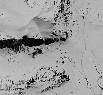 "Dette satellittbildet er tatt våren 1970 og dekker omtrent det samme området som forrige bilde. Det mørke feltet som går inn i bildet fra venstre er skyggen av selve fjellet. Flekken under der igjen er selve basen. Stripene som er tydelige, er spor etter kjøretøy i snøen. Basen var nok under bygging da bildet ble tatt, og er klart den største basen som ble bygget her, sett bort fra hovedbasen ved kysten." "Dette satellittbildet er tatt våren 1970 og dekker omtrent det samme området som forrige bilde. Det mørke feltet som går inn i bildet fra venstre er skyggen av selve fjellet. Flekken under der igjen er selve basen. Stripene som er tydelige, er spor etter kjøretøy i snøen. Basen var nok under bygging da bildet ble tatt, og er klart den største basen som ble bygget her, sett bort fra hovedbasen ved kysten."