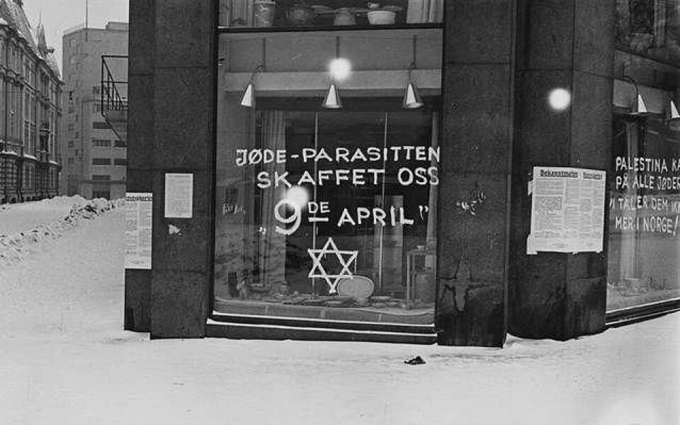 Antisemittisk grafitti på et butikkvindu i Oslo i 1941. Teksten på vinduet i forgrunnen sier 'Jøde-parasitten skaffet oss 9de april'. På ruta rundt hjørnet står 'Palestina kaller på alle jøder. Vi tåler dem ikke mer i Norge'. (Foto: Anders Beer Wilse (1865–1949)/Wikimedia Commons)