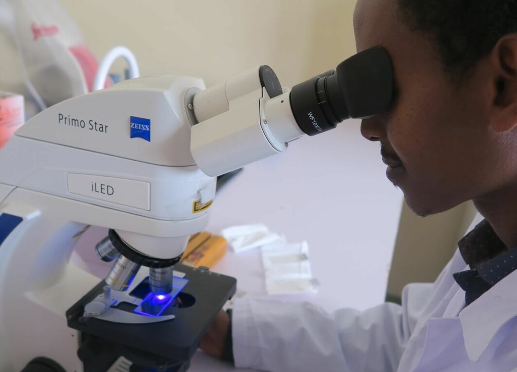 En helsearbeider i Etiopia ser i et LED-mikroskop.