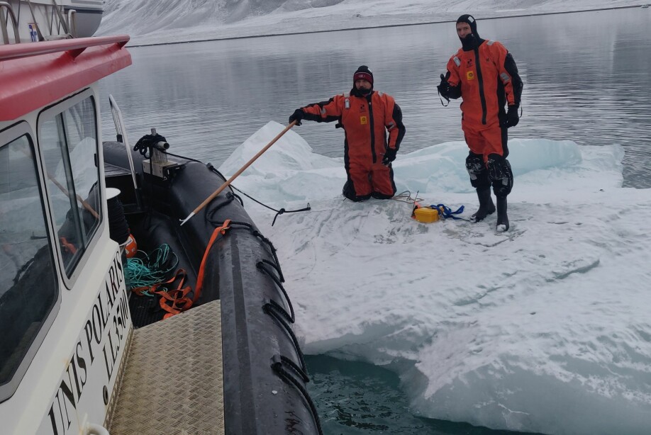 Aleksey Marchenko fra Universitetssenteret på Svalbard (UNIS) og Trygve Kvåle Løken (t.h.) gjør isfjellet klart til taueeksperiment.