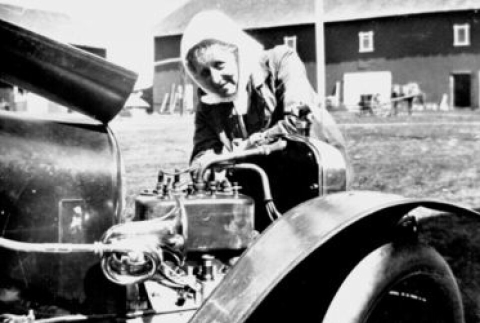 Thora Løken var første kvinne som tok sertifikat i Hedmark i 1914. Her mekker hun på bilen sin utenfor Granerud gård i Veldre. (Foto: Ukjent person/Hedmarksmuseet)