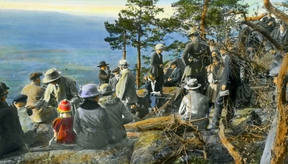 During the interwar period, a growing number of hikers visited Oslomarka, where they could follow the multiplying choice of paths waymarked with blue blazes. The association for “Friluftsliv og Kropskultur” (outdoor pursuits and physical culture) gathered at Kolsåstoppen in Bærum in the summer of 1920. Hand-coloured photograph.