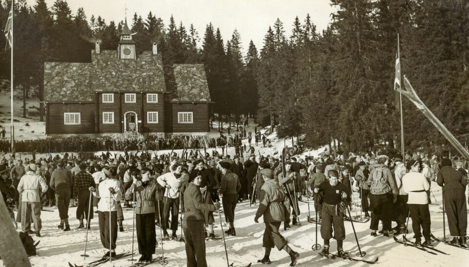 Sunshine and, most probably, good conditions for skiing: Large group skiing in front of the old Ski Museum at Frognerseteren, 1920s.