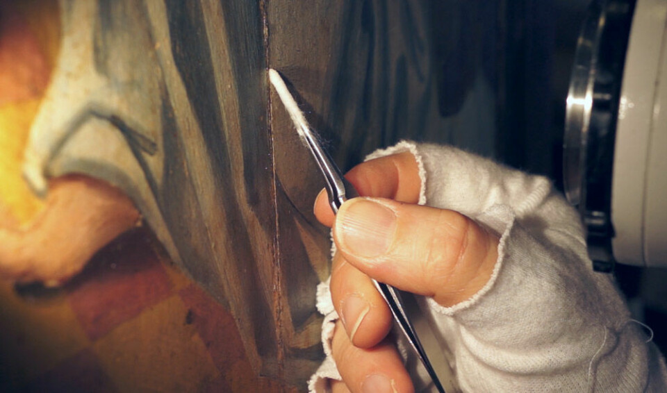 Malerikonservator Barbro Wedvik ved Norsk institutt for kulturminneforskning fjerner lim som kan skade malingen på døren til alterskapet i Ørsta kirke. (Foto: Arnfinn Christensen)