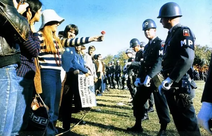 En kvinnelig demonstrant rekker fram en blomst til amerikansk militærpoliti i 1967. (Foto: Wikimedia Commons)