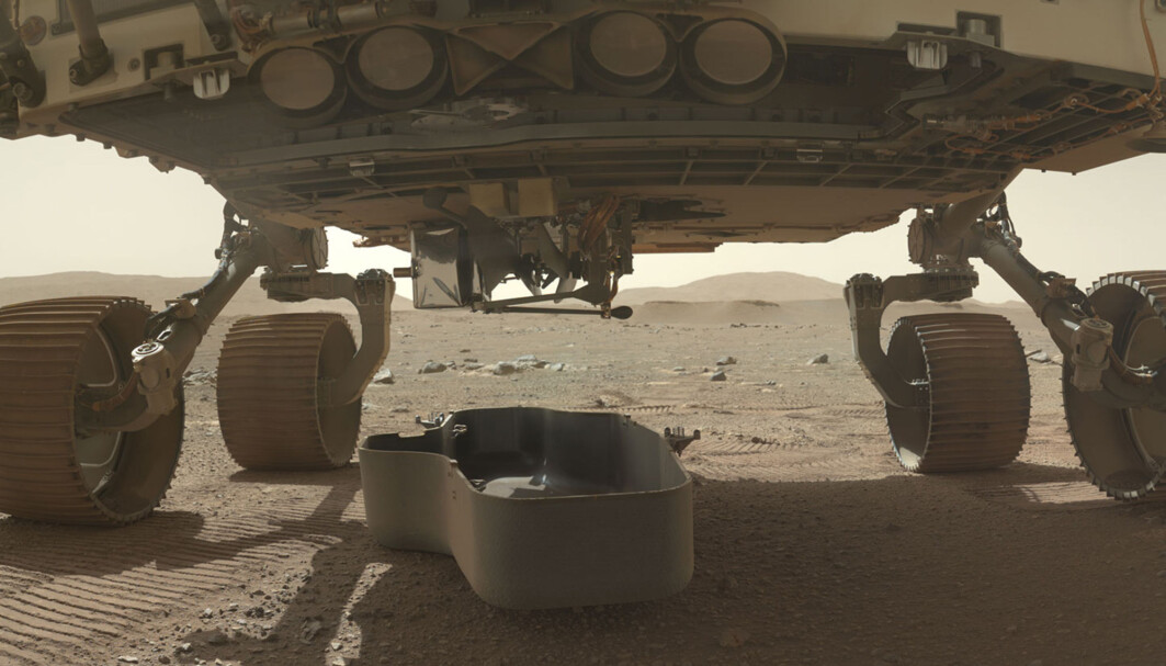 Et bilde offentliggjort av Nasa søndag viser den lille helikopterdronen Ingenuity, som er brettet sammen og koblet fast til undersiden av robotfarkosten Perseverance på Mars. Skjoldet som har beskyttet den, er nylig koblet fra. Det kan ses på bakken under. Et bilde offentliggjort av Nasa søndag viser den lille helikopterdronen Ingenuity, som er brettet sammen og koblet fast til undersiden av robotfarkosten Perseverance på Mars. Skjoldet som har beskyttet den, er nylig koblet fra. Det kan ses på bakken under.