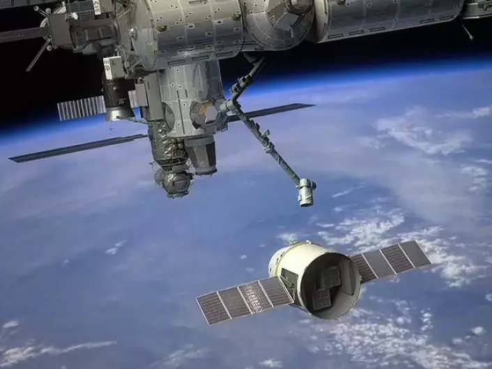 Dragon-kapselen i ferd med å bli hentet inn av robotarmen på den internasjonale romstasjonen. (Foto: (Illustrasjon: NASA))