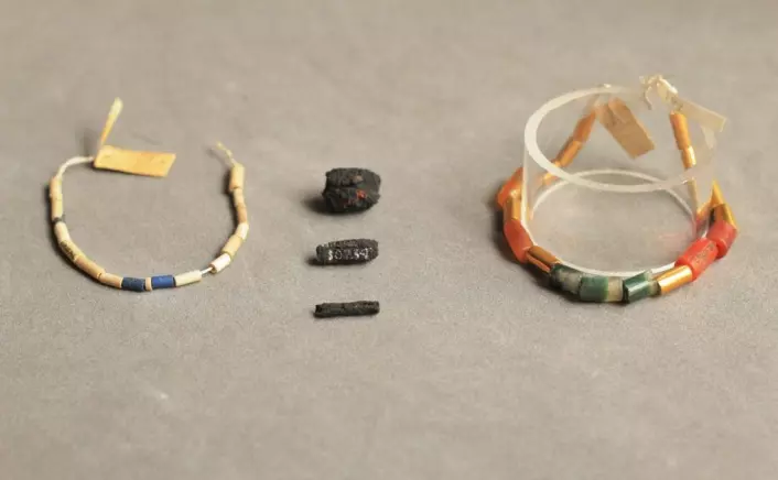 Meteorittjern-bitene ligger i midten av bildet. Bildet viser også sylinderne med blå lasurstein (til venstre), og rødlig karneol, agate og gull (til høyre), som meteorittjern-sylinderne opprinnelig var tredd sammen med. (Foto: UCL Petrie Museum/Rob Eagle)