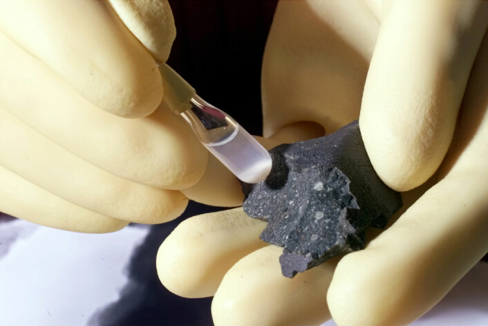 En del av Murchison-meteoritten som ble funnet i Australia i 1969, med partikler fra meteoritten i et testrør. En ny analyse i 2010 viste at meteoritten inneholdt over 14 000 forskjellige organiske stoffer, blant dem 70 aminosyrer, byggesteiner til liv. (Foto: US Department of Energy/Wikimedia Commons)