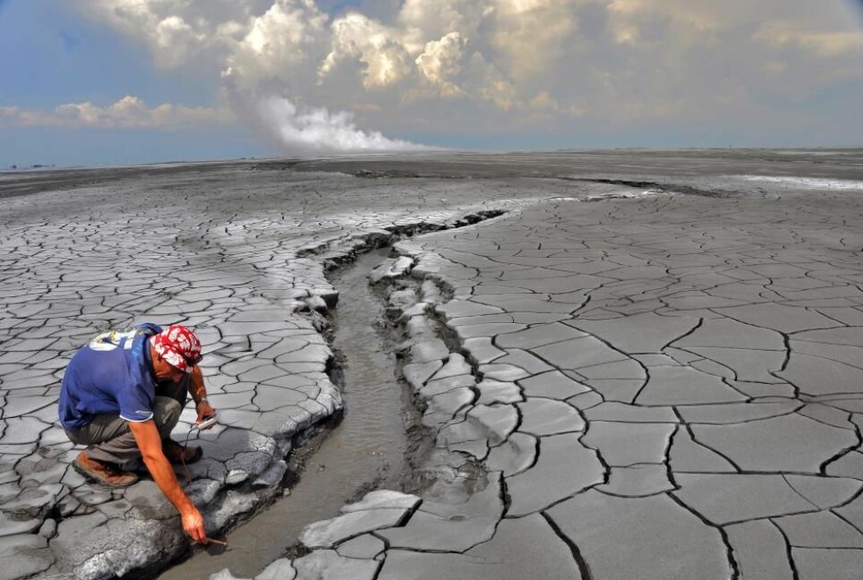 The Lusi eruption: A non accessible 650 m in diameter hot mud pond surrounds the central vents zone (rising plume is seen in the horizon). The erupted mud reaches temperatures of 100 °C and extensive oil slicks can be observed.