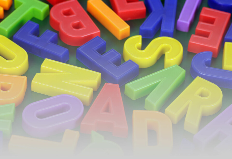 Background photo of magnetic alphabet letters.  Focus is across the middle.