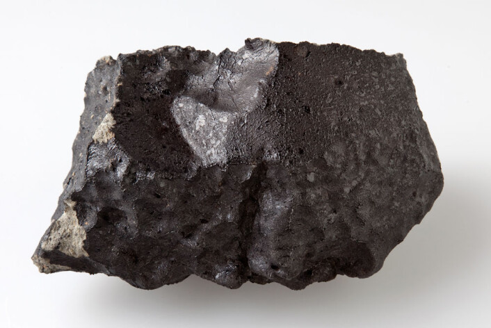 Baksida av den 1,1 kilo tunge steinen er nesten helt dekt av blank, svart smelteskorpe som ble dannet under meteorenes heite ferd igjennom atmosfæren. (Foto: Natural History Museum, London) Baksida av den 1,1 kilo tunge steinen er nesten helt dekt av blank, svart smelteskorpe som ble dannet under meteorenes heite ferd igjennom atmosfæren. (Foto: Natural History Museum, London)