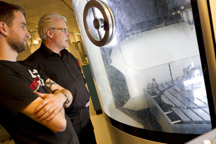 – I denne maskinen lager jeg nå små biter for nanolab’en på NTNU, sier finmekaniker Øystein Hagemo. Til høyre: Harald Snekvik, avdelingsleder ved Finmekanisk verksted, NTNU. (Foto: Ole Morten Melgård) – I denne maskinen lager jeg nå små biter for nanolab’en på NTNU, sier finmekaniker Øystein Hagemo. Til høyre: Harald Snekvik, avdelingsleder ved Finmekanisk verksted, NTNU. (Foto: Ole Morten Melgård)