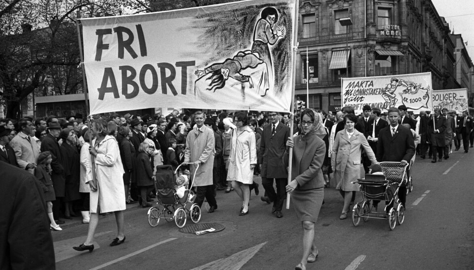 Kvinners liv og helse har lenge vært et viktig tema for de som ønsket å gjøre abort mulig. Her passerer demonstranter med en plakat som skal illustrere hva som kan skje hvis kvinner ikke får mulighet til å ta abort på sykehus. Første mai-toget Stortinget på vei ned Karl Johans gate i 1968.