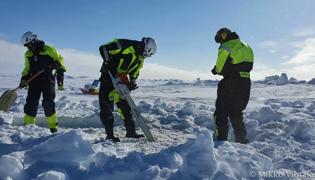 Amalia, Peter and Håkon lager et dykkehull i den 1,5 tykke isen i kaldt vintervær. På Svalbard så blir været målt i hva en trenger å ha på seg den dagen. Denne dagen var det en “Balaclavadag”