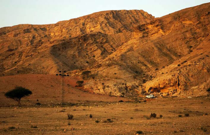 Arkeologer har funnet 120 000 år gamle spor av mennesker ved Jebel Faya i De forente arabiske emirater. Steinalderboplassen ligger rett bak den hvite bilen i bildet. (Foto: Science/AAAS) Arkeologer har funnet 120 000 år gamle spor av mennesker ved Jebel Faya i De forente arabiske emirater. Steinalderboplassen ligger rett bak den hvite bilen i bildet. (Foto: Science/AAAS)