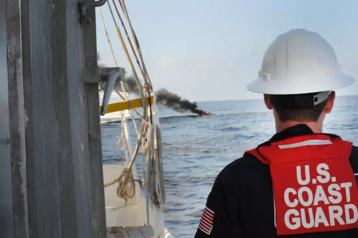 "En amerikansk kystvaktsoldat følger med på kontrollert brenning av olje i Mexicogolfen. (Foto: US Navy ved Petty Officer 1st Class Jeffery Tilghman Williams)"